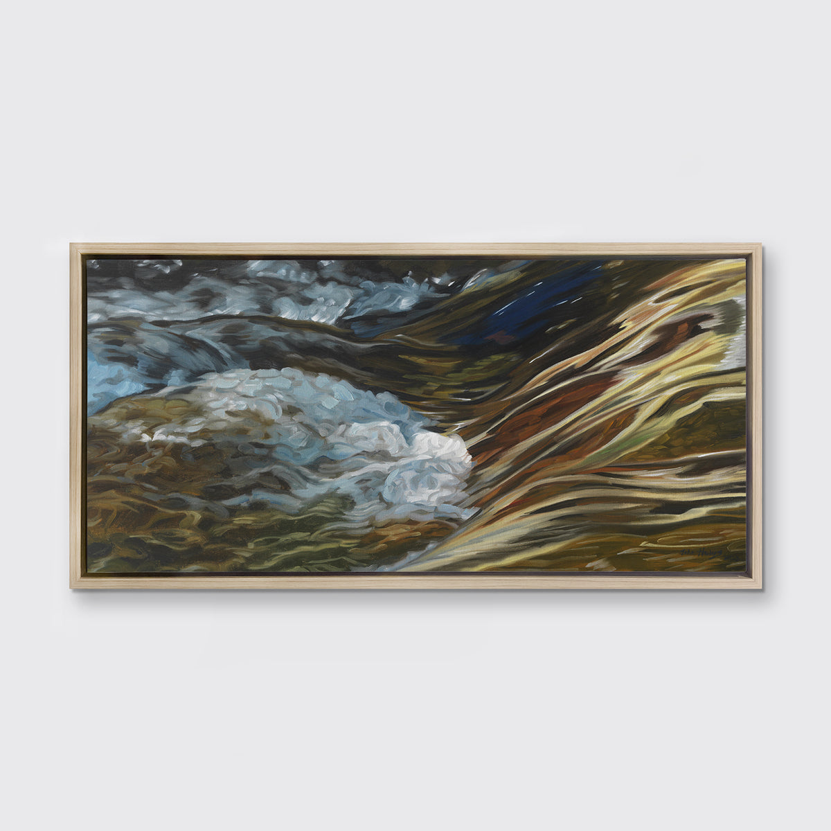 A painting of bubbling water flowing in a rocky river in a white oak frame hangs on a white wall.