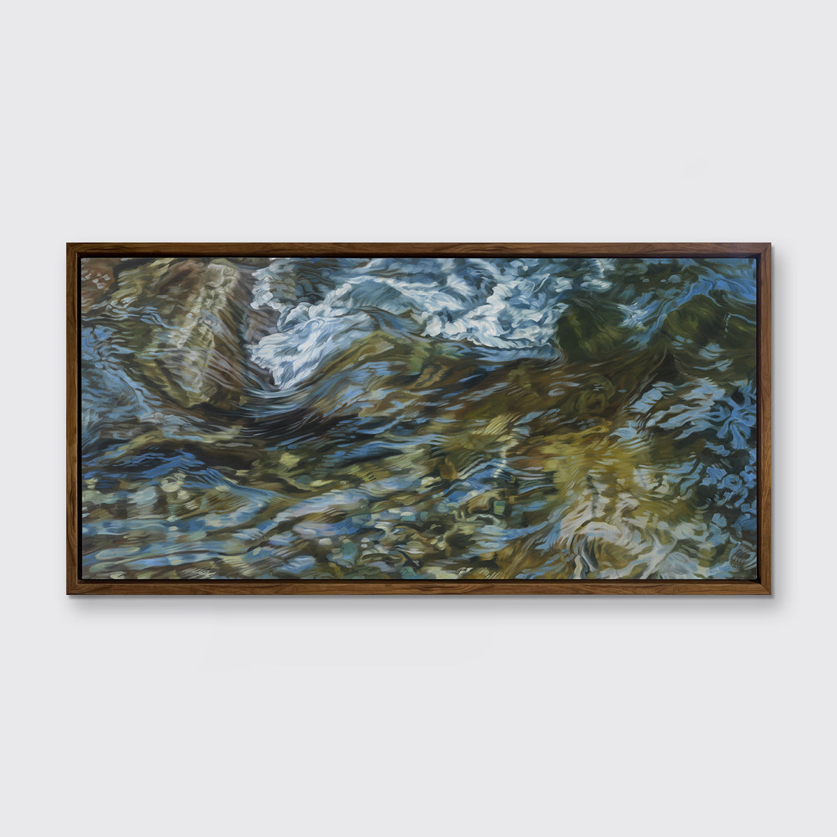 A painting of flowing water in a rocky riverbed in a dark oak frame hangs on white wall.