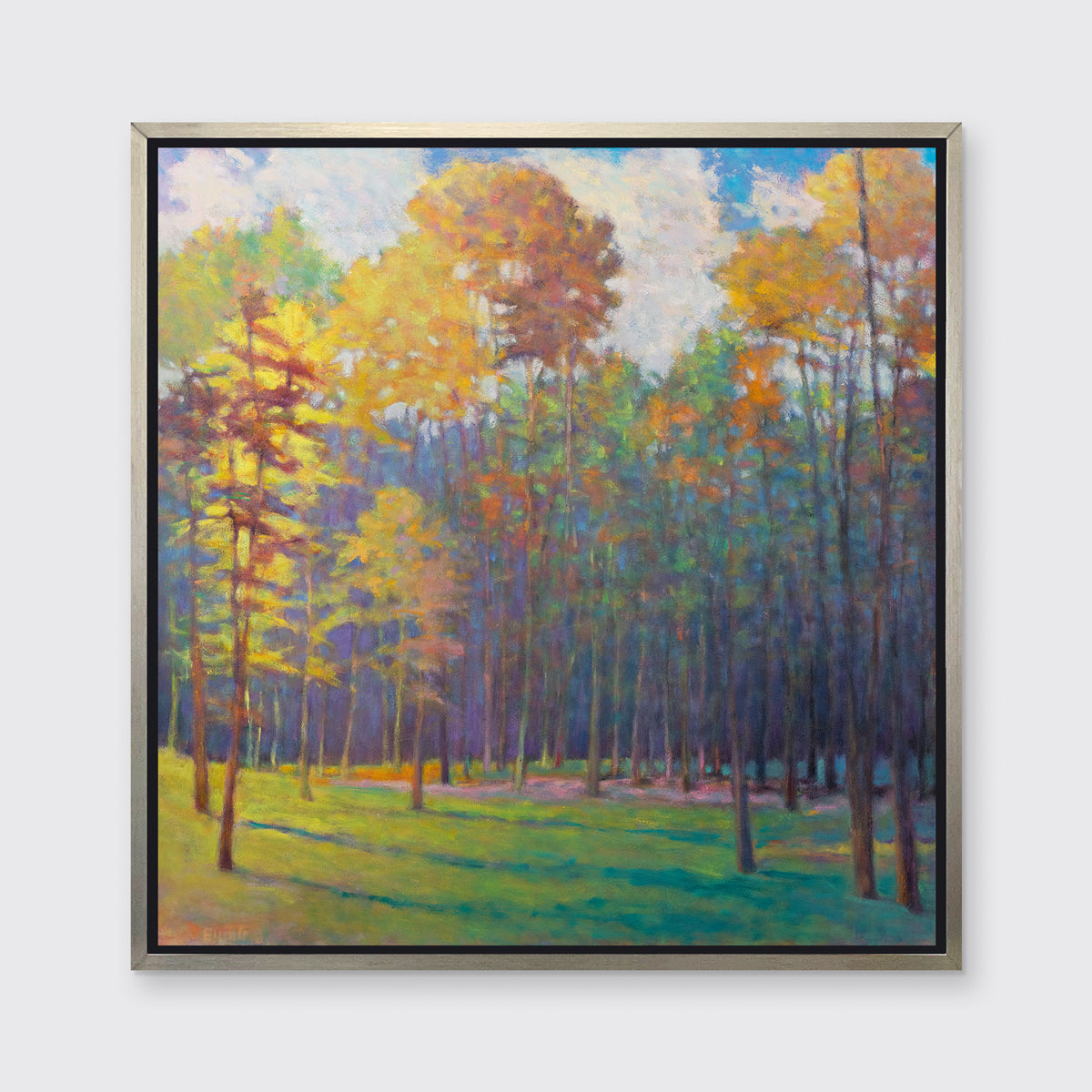 An impressionist landscape print in a silver floater frame hangs on a white wall.