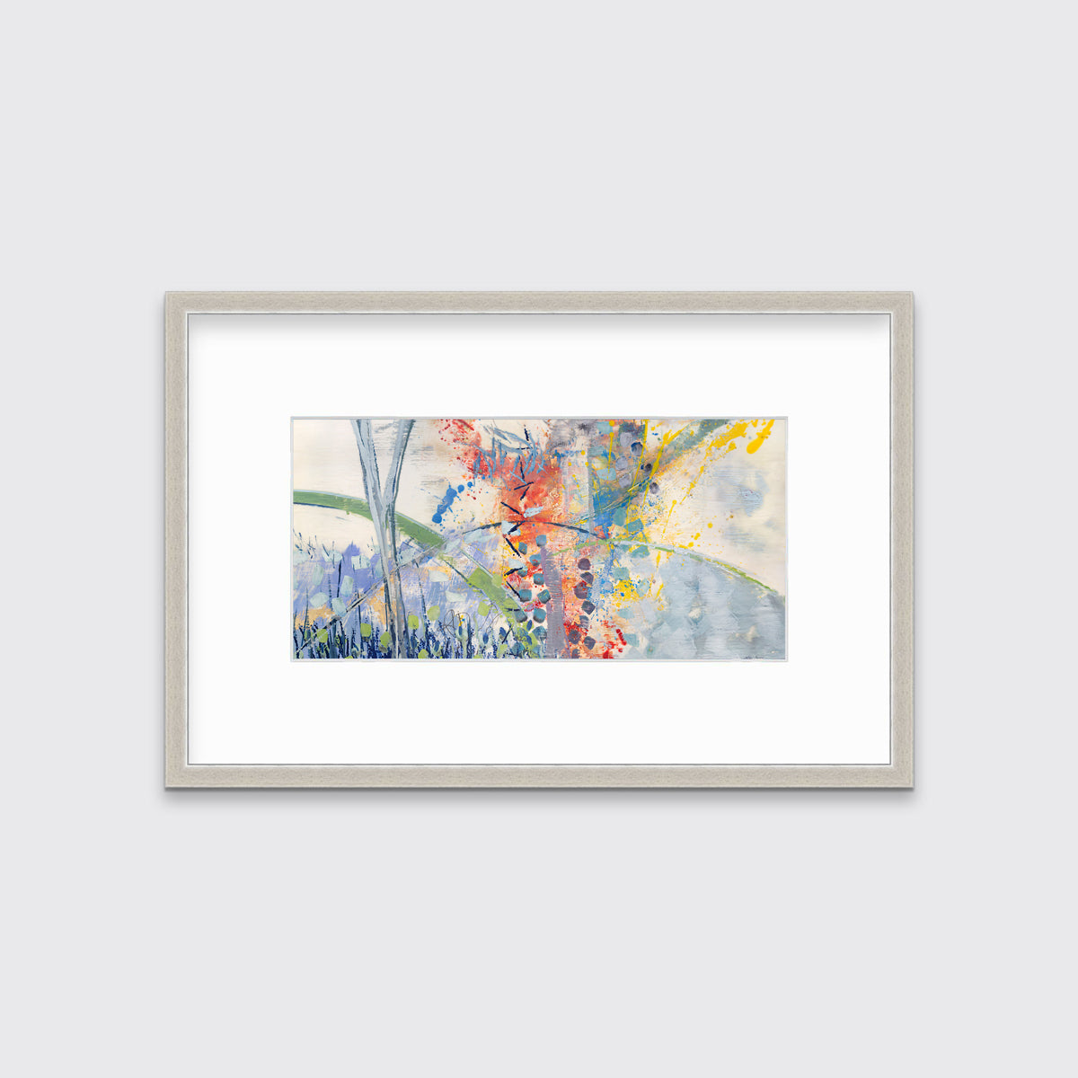 A multicolored abstract print in a silver frame with a mat hangs on a white wall.