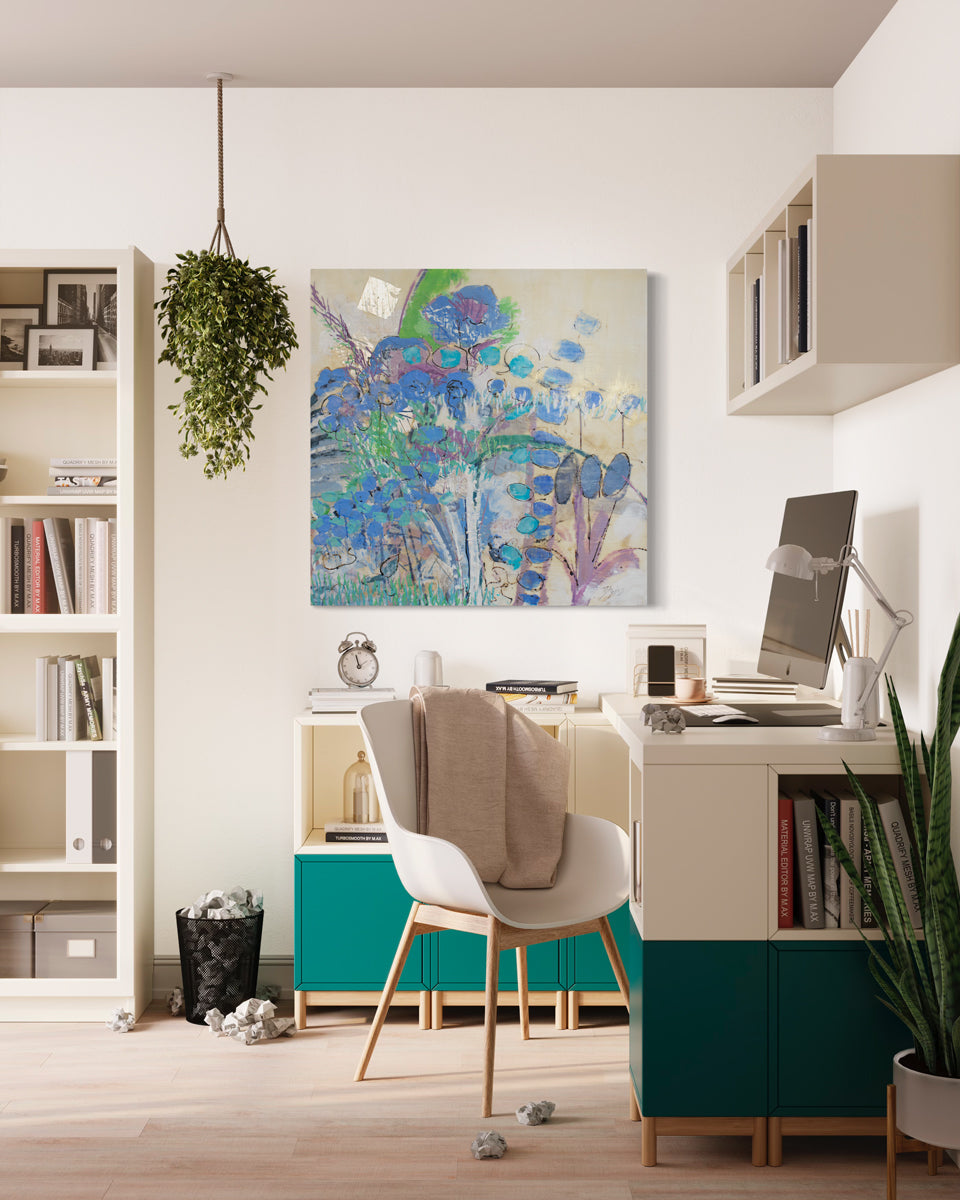 A blue and green abstracted encaustic painting hangs on a white wall above a green and white modern office desk with a computer, floating shelving, and a white bookcase to the left. 