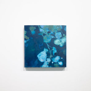 A blue abstract floral painting hangs on a white wall. 