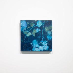 An abstract blue floral painting hangs on a white wall. 