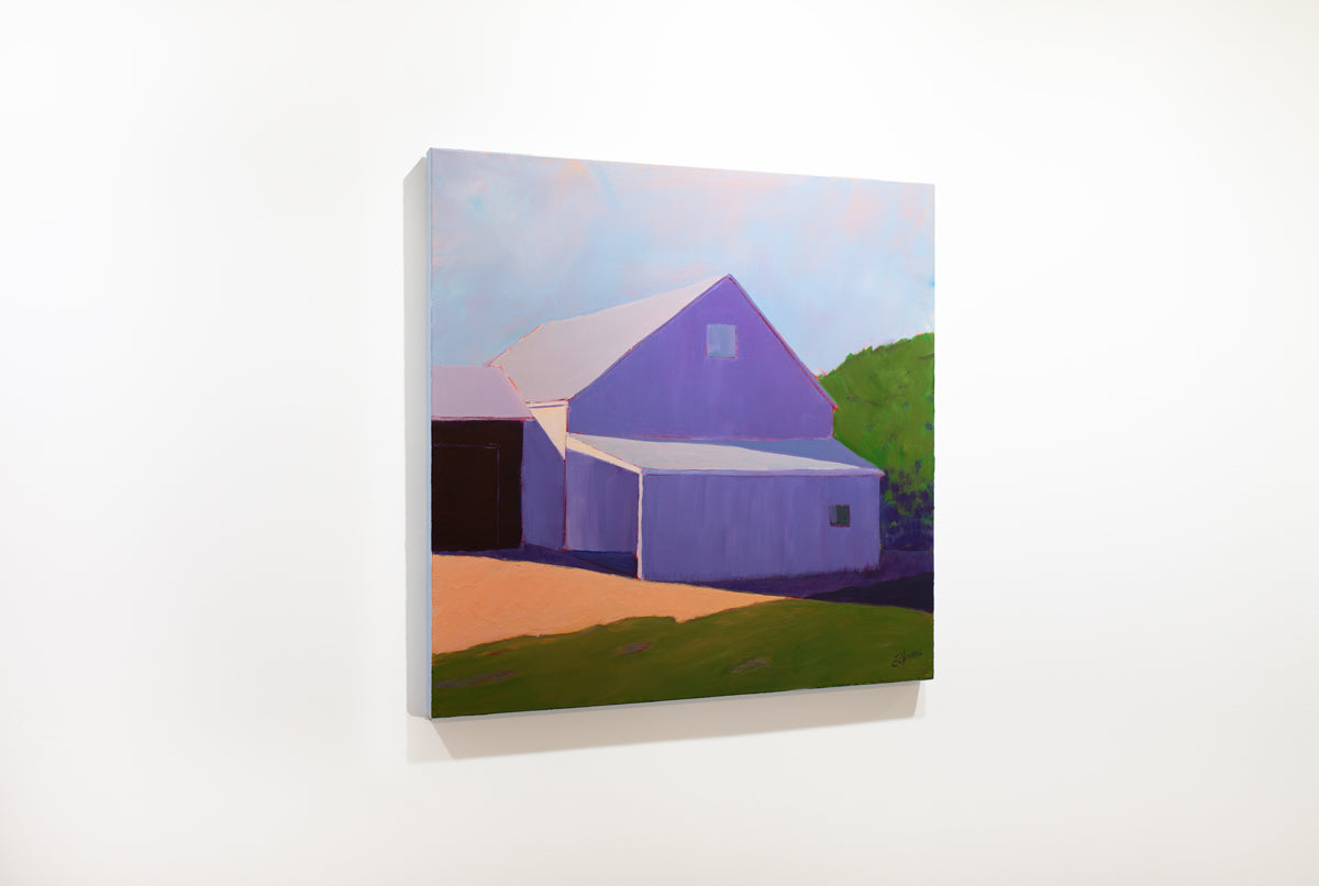 A left side view of a landscape painting of a barn in lavender shadow, blue sky and green hedges by Carol Young.