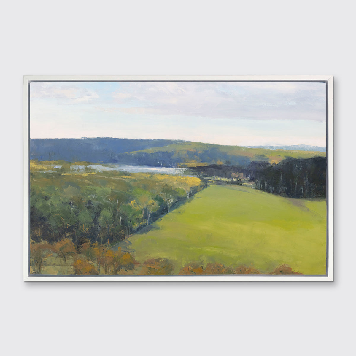 A landscape print in a white floater frame hangs on a white wall.