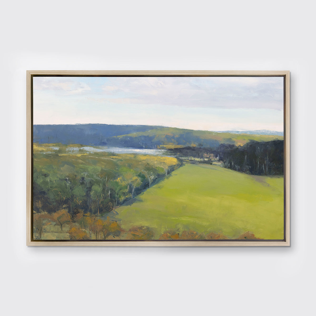 A landscape print in a white oak wood floater frame hangs on a white wall.