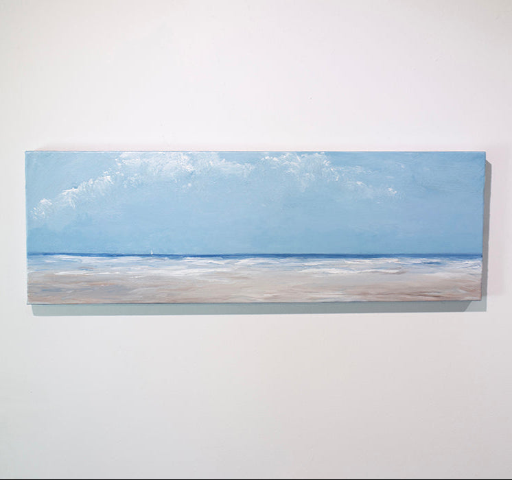 A textured blue and beige coastal painting of a beach hangs on a white wall.