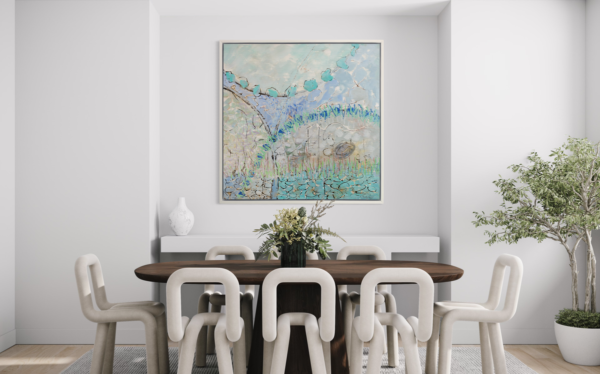 A teal, lavender, black and grey abstract print in a white floater frame hangs on a white wall above a floating white shelf and a large wood dining table with eight modern white cutout chairs.