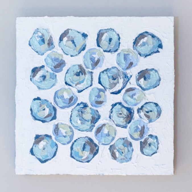 A very textured abstract painting with white background and circle type abstract flowers in blue, teal, green, plum and white hangs on a grey wall.