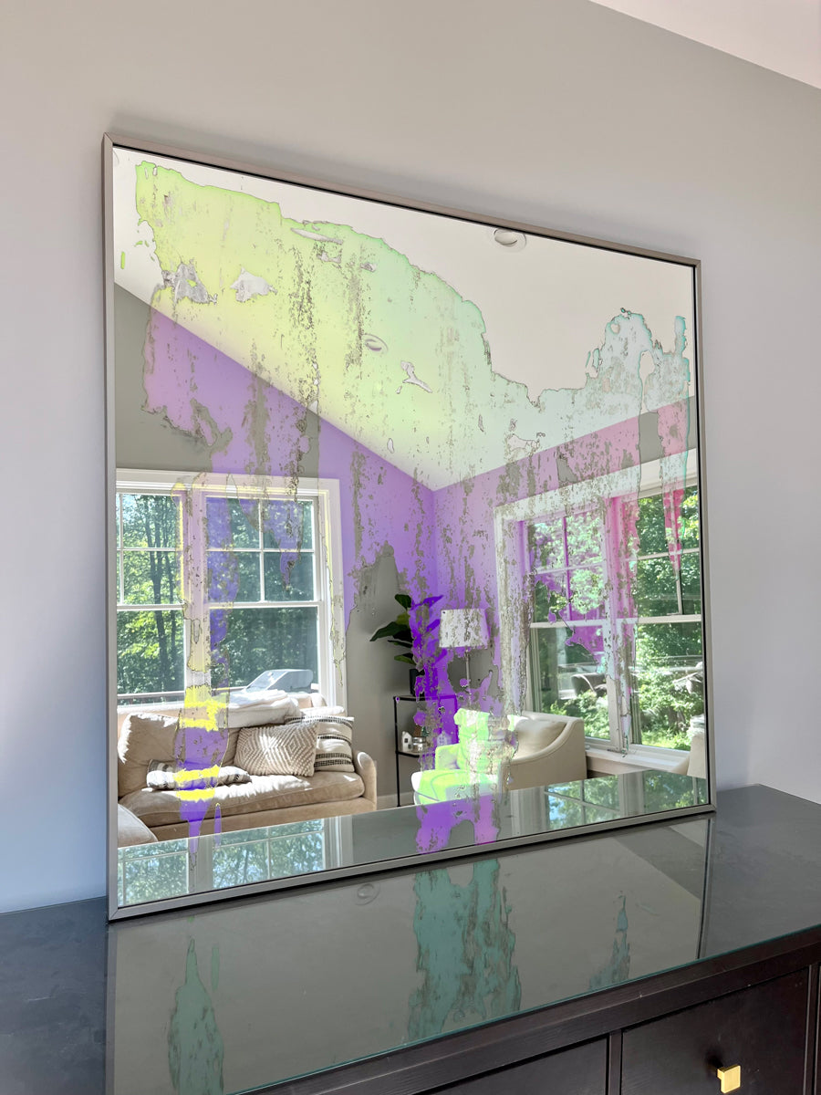 An original fine art mirror by Alina B rests on a wood dresser. 