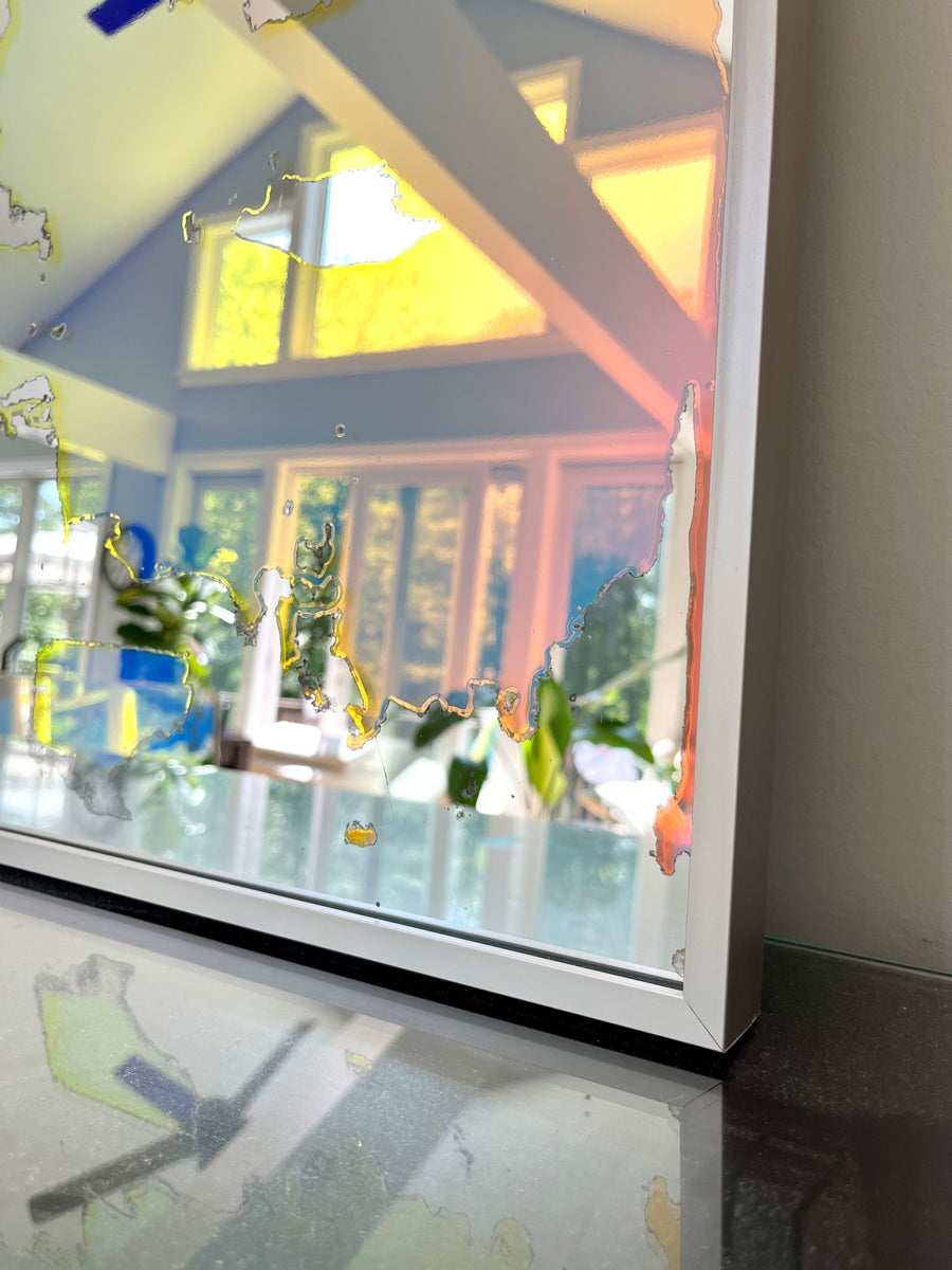 A corner of a framed fine art mirror. 