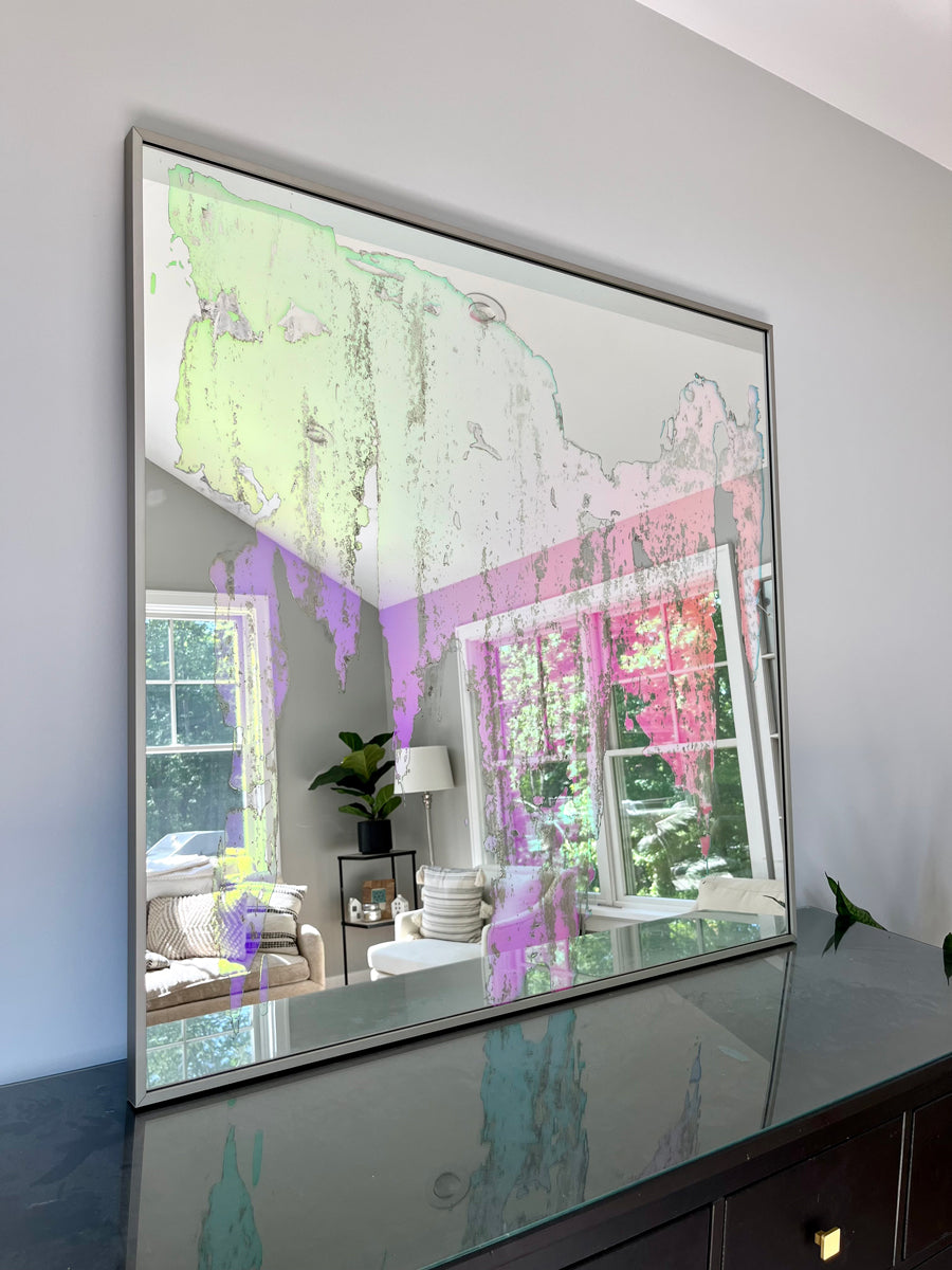 An original fine art mirror by Alina B rests on a wood dresser.