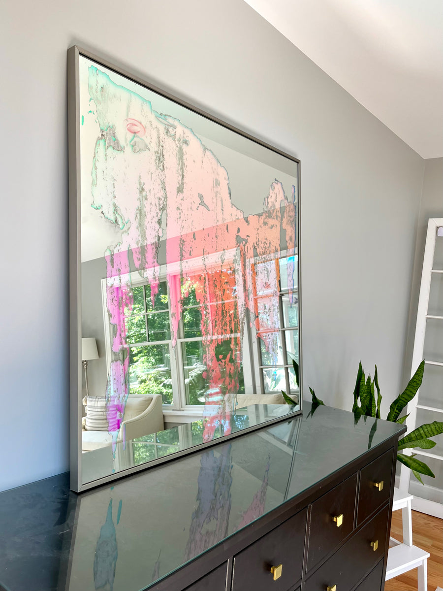 An original fine art mirror by Alina B rests on a wood dresser.