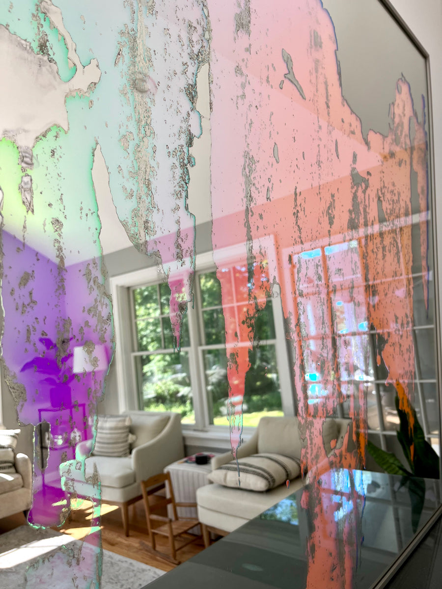 A detail of a fine art mirror reflects the room it is in.