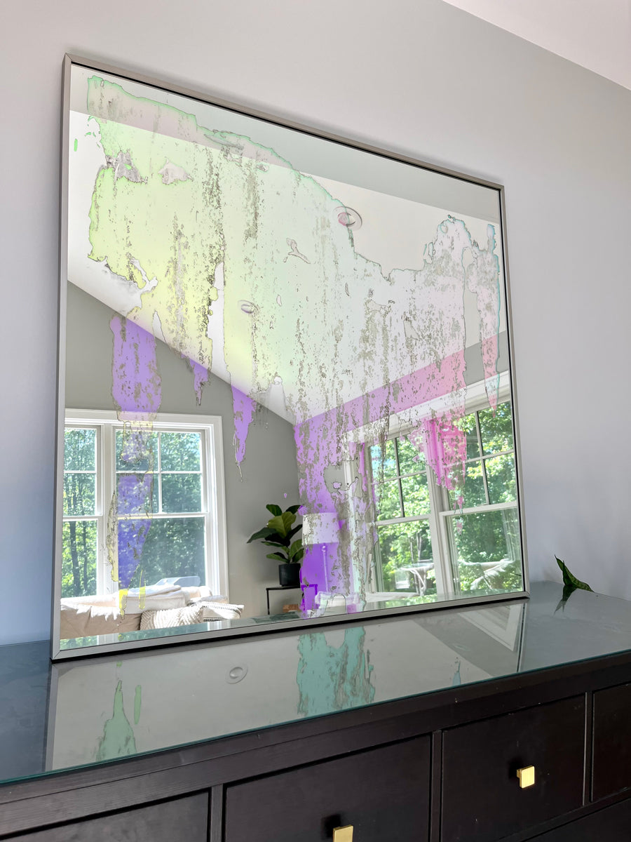 An original fine art mirror by Alina B rests on a wood dresser.
