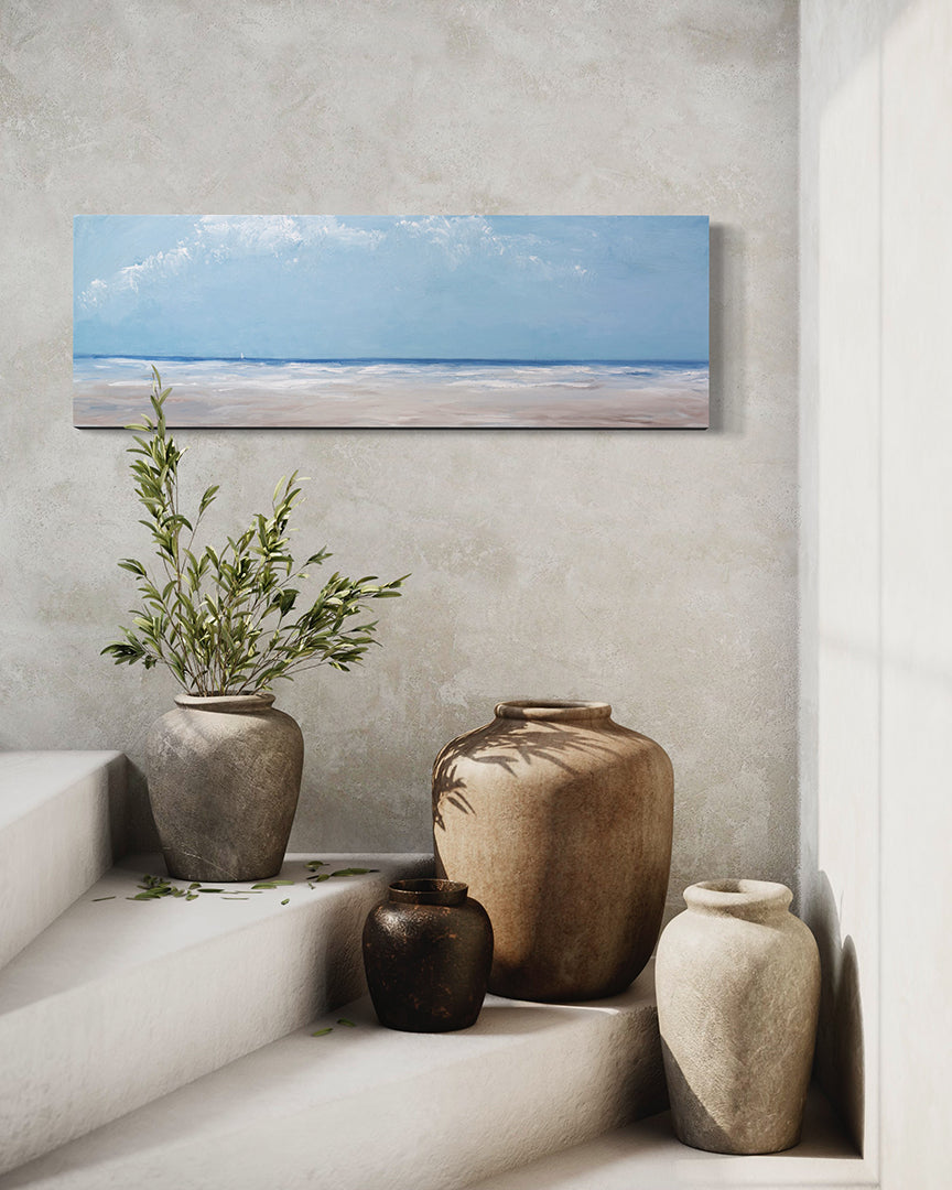 A textured blue and beige coastal painting of a beach hangs on a fresco wall above a staircase with large ceramic vases and a potted plant. 