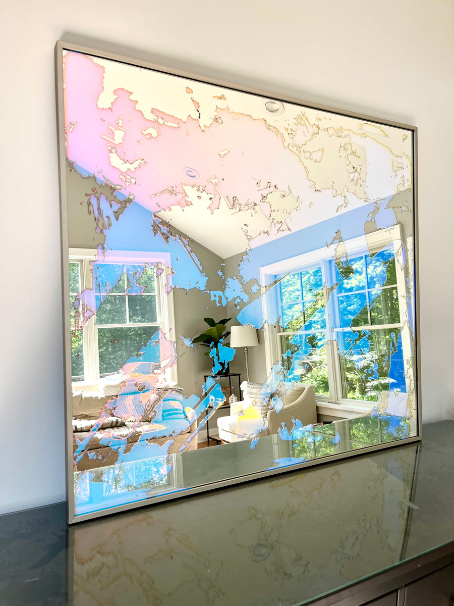 A fine art mirror rests on a wood dresser.