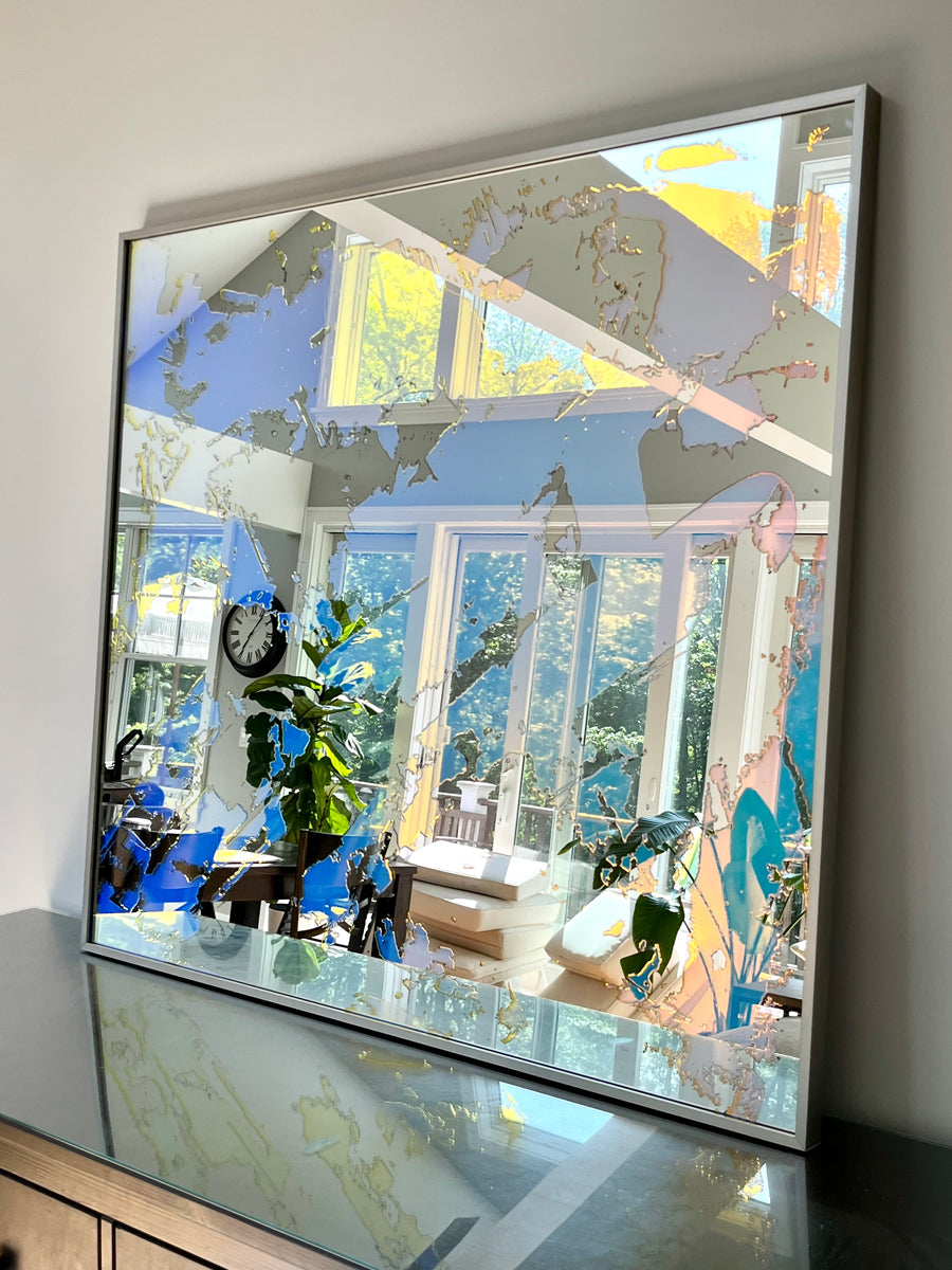 A fine art mirror rests on a wood dresser.
