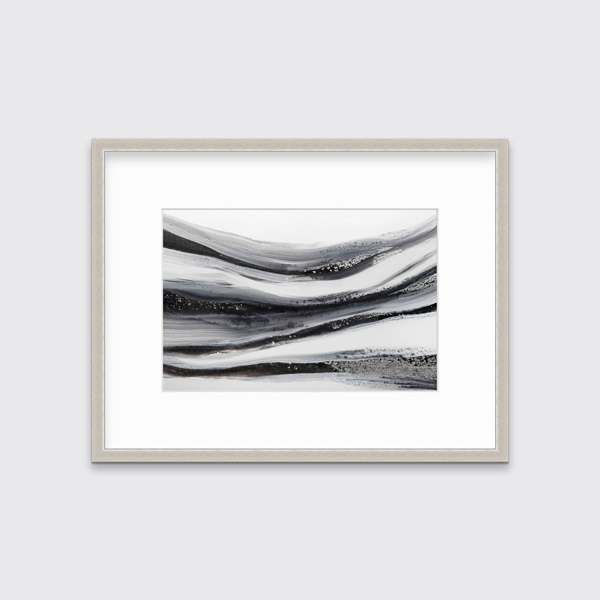 A black, white and grey abstract print in a silver frame with a mat hangs on a white wall.
