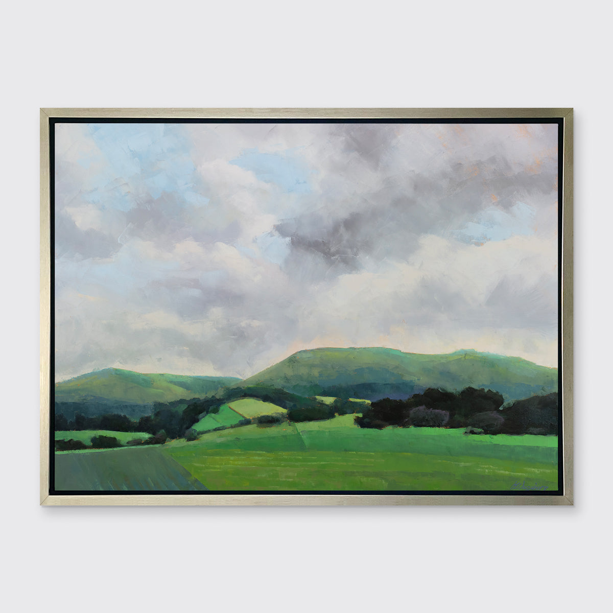 A landscape print in a silver floater frame hangs on a white wall.
