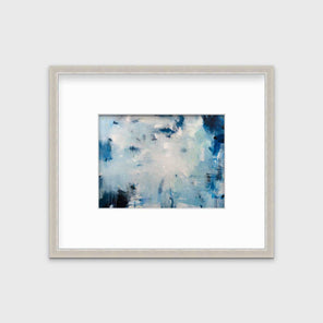 A blue and white abstract print by Kelly Rossetti in a silver frame with a mat hangs on a white wall.