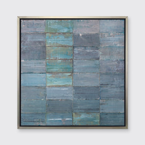 An abstract geometric slate blue and sea foam green limited edition art print by Ned Martin framed in a silver frame hangs on a grey wall.
