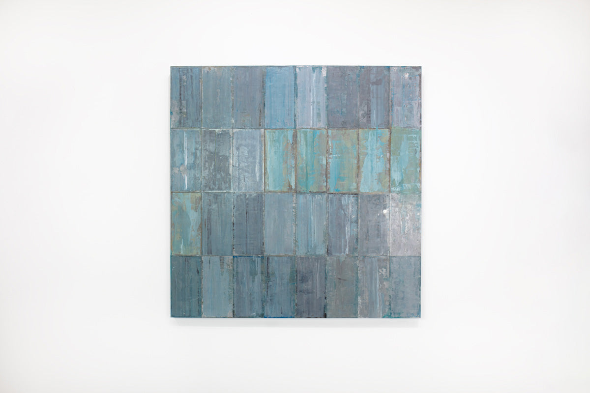 A blue and grey abstract geometric painting hangs on a white wall.