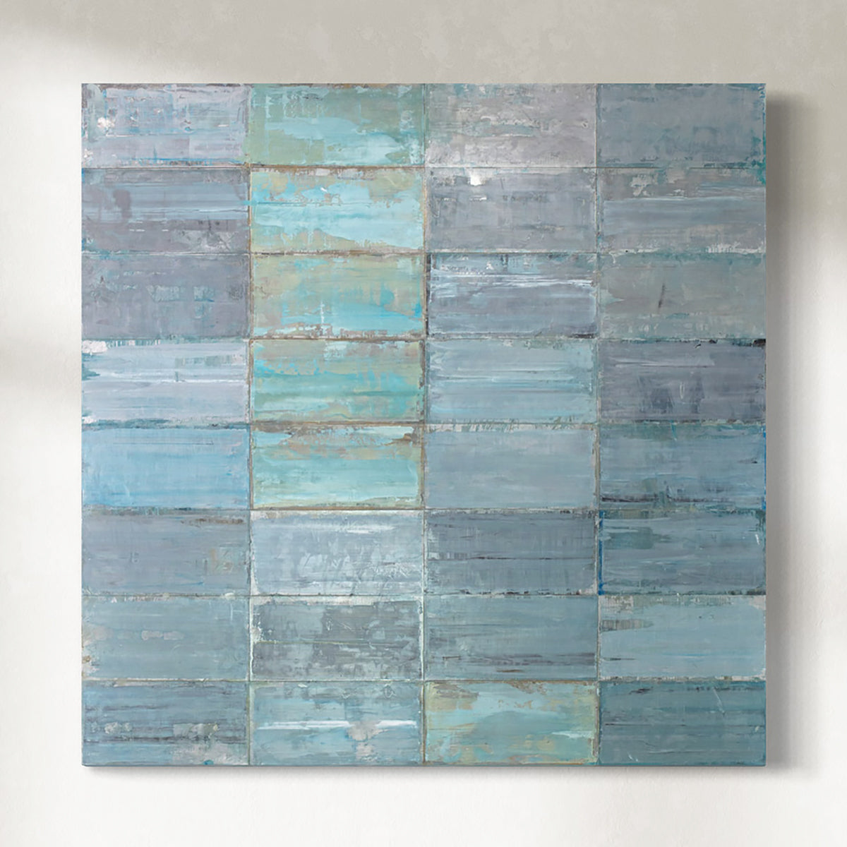 Square original painting with horizontal blue and gray stripes on metal plates hanging on a white wall.