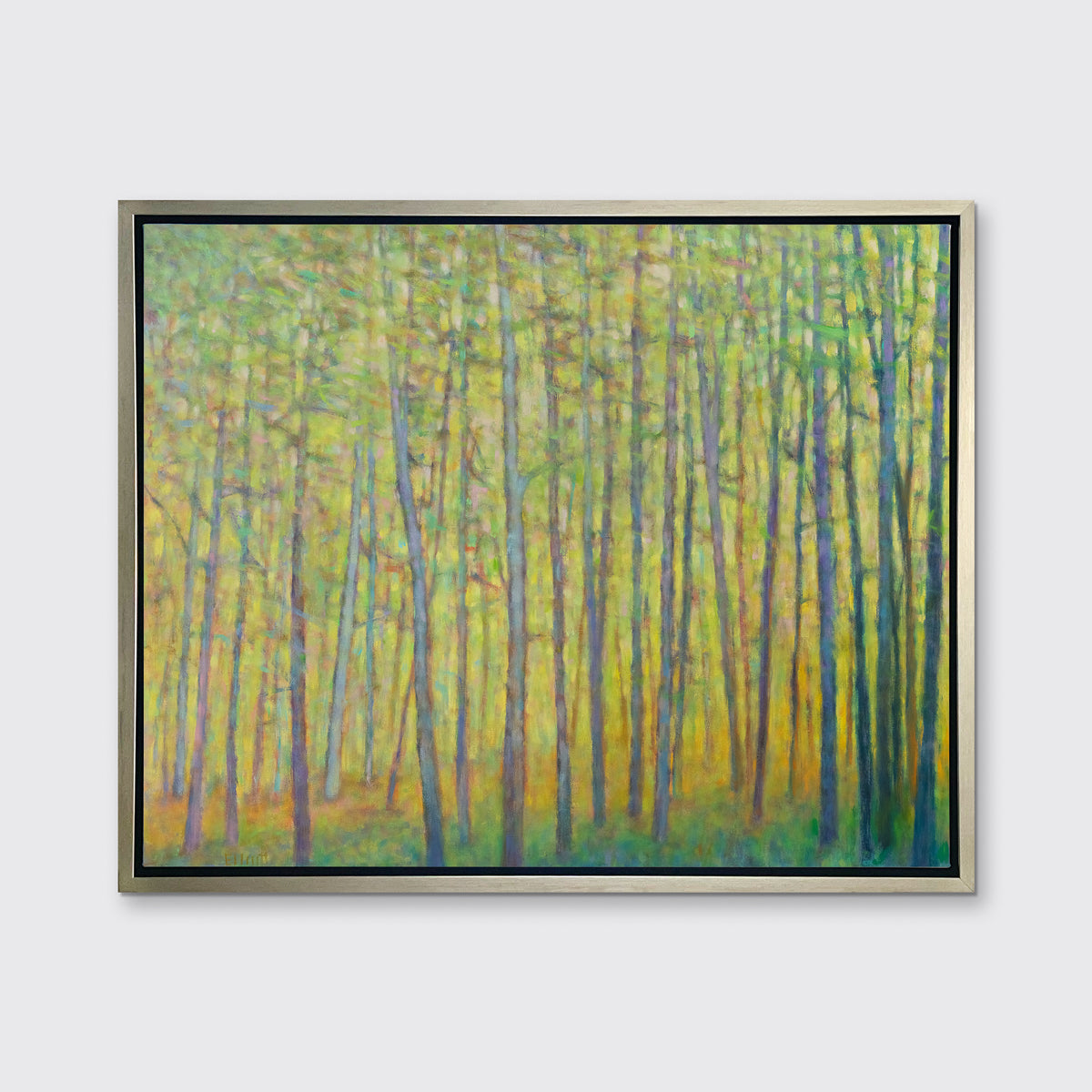 A green and yellow impressionist landscape print in a silver floater frame hangs on a white wall.