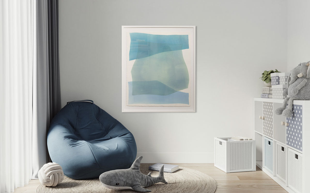 A large framed abstract painting hangs on a white wall in a child's play room with a large blue bean bag chair, stuffed animals, and a white shelving unit. 