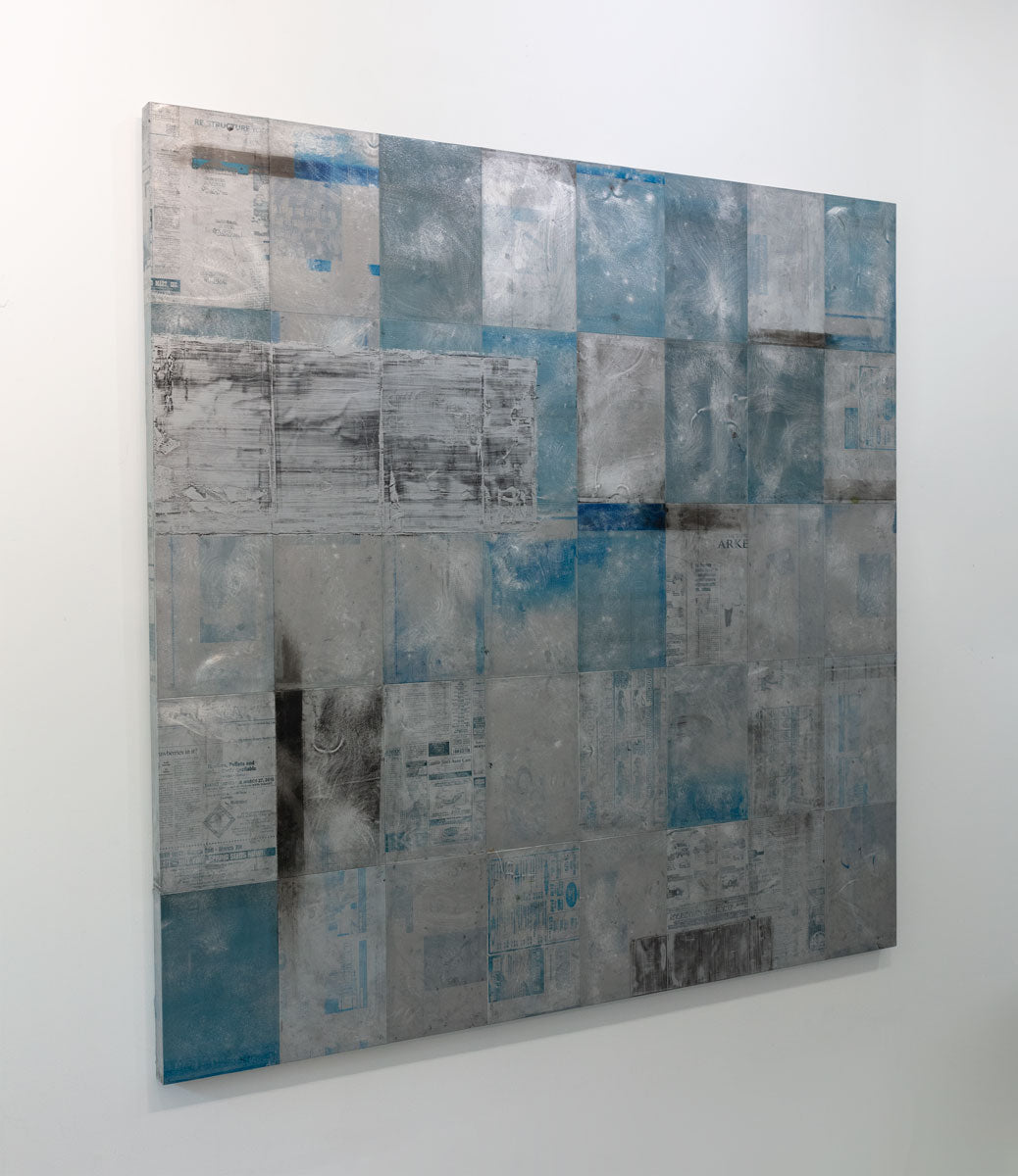 A blue painting on recycled metal print plates is seen at an angle on a gallery wall.