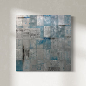 A blue painting on recycled metal print plates is hung on a gallery wall.