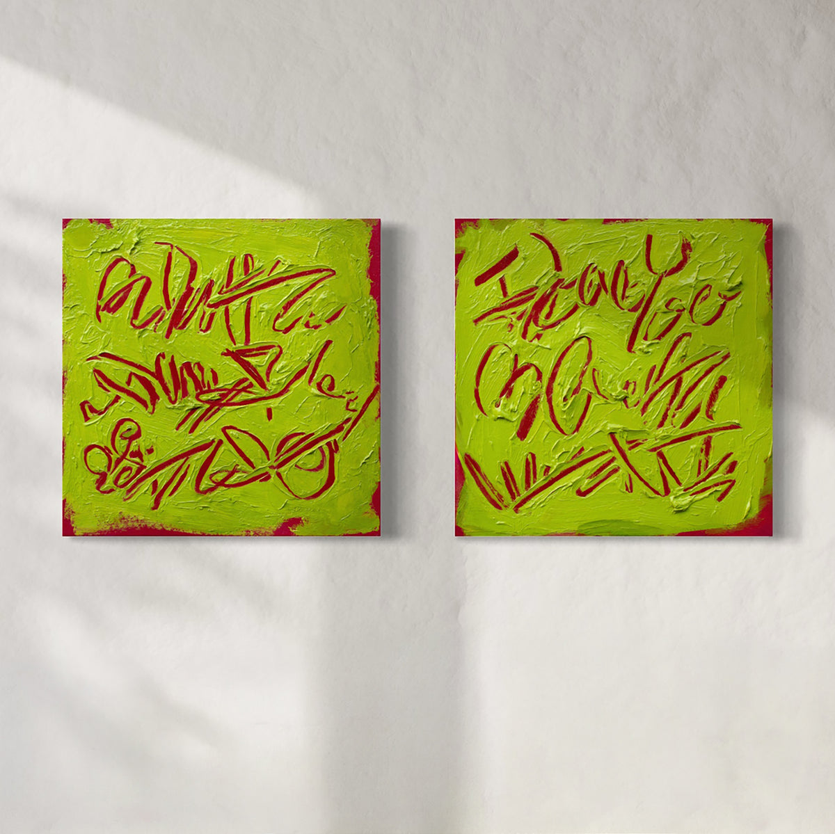 Two square abstract text-based paintings with textured chartreuse over hot raspberry pink  graffiti-style lettering, displayed side-by-side on a white wall.