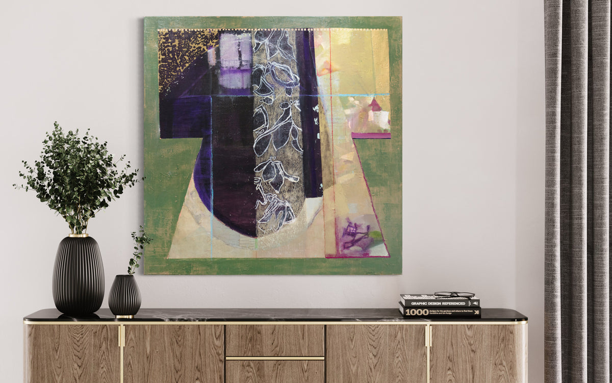 A green, gold, black and purple abstract painting by Christine Averill-Green hangs on a white wall above a black marble and wood credenza with greenery filled black ribbed vases and a stack of books.