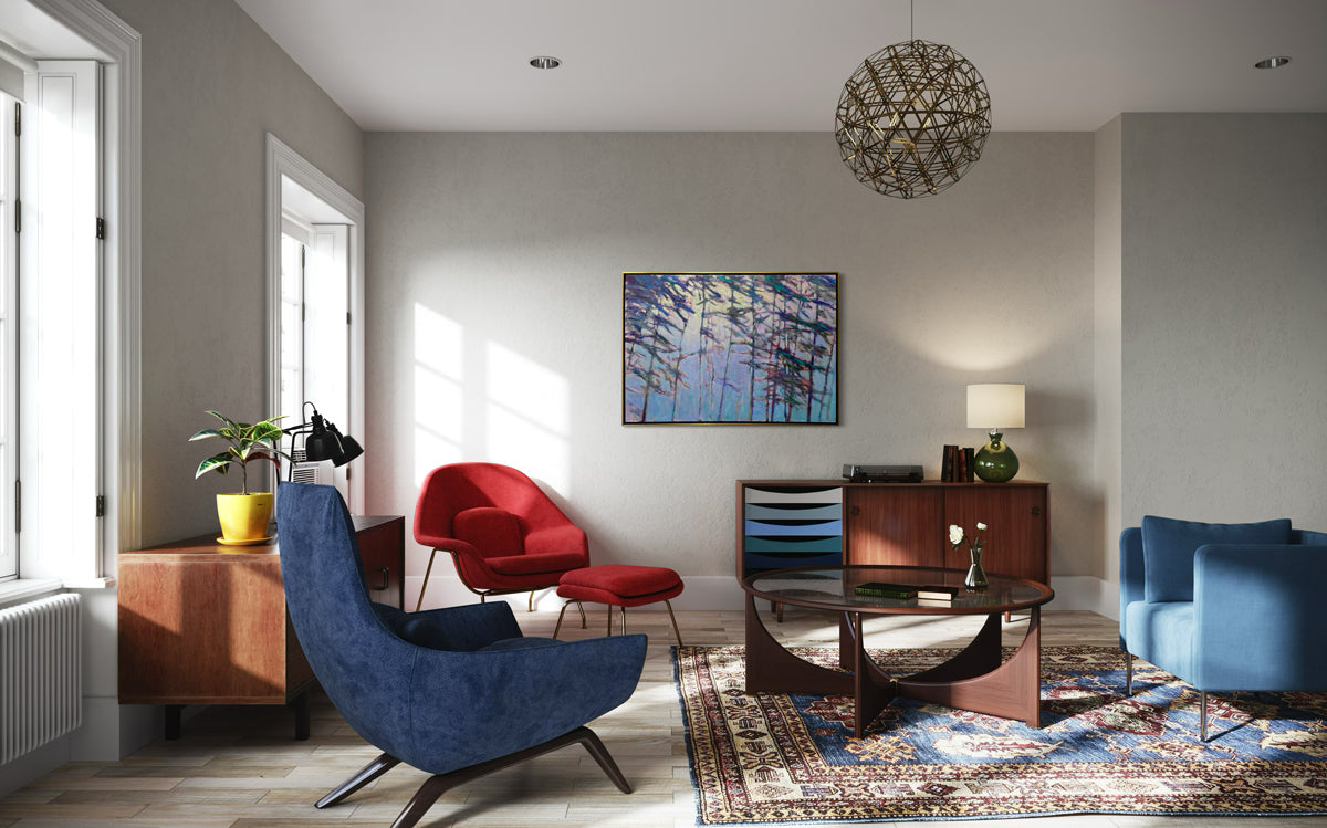 An impressionistic landscape painting by Ken Elliott in the of trees with blue and purple leaves in a gold floater frame hangs on a white wall similar to the spirit of the late artist Wolf Kahn, hangs on a white wall in a living room.