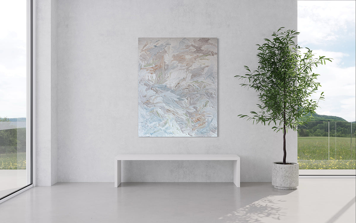 An abstract painting with thickly textured brushstrokes of beige, green, orange, and blue is hung in a modern room with floor to ceiling windows and a potted tree to the right.