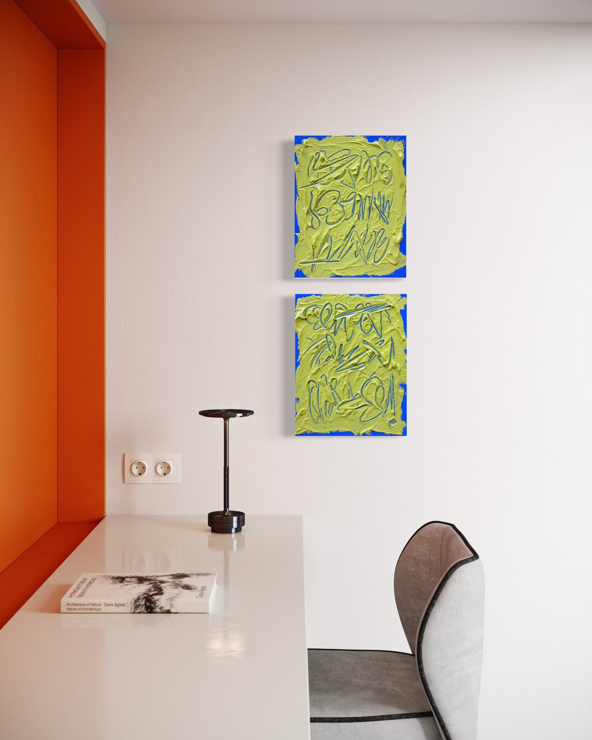 Two abstract text based paintings feature a thick, yellow-green impasto texture with blue abstract scribbled lines and a bright blue base and hang on a white wall in a modern room with an orange accent wall, white desk, and gray chair.