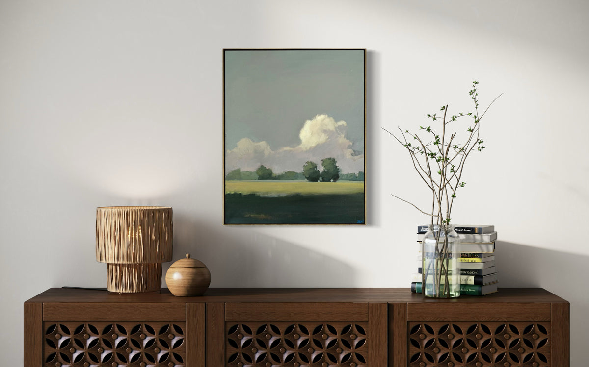 Framed landscape painting on a wall above a wooden console table with decorative items.