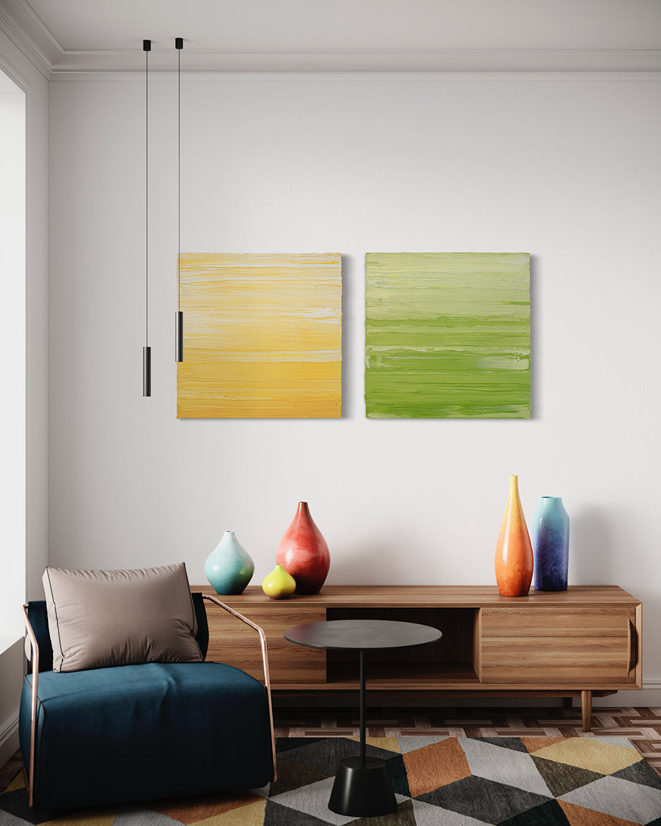 Two textured abstract paintings, one in yellow and white and the other in chartreuse and white by Teodora Guererra hang on a wall over a credenza with bright colored ceramic pots.