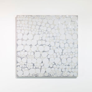 An abstract white, beige, and grey painting hangs on a white wall. 