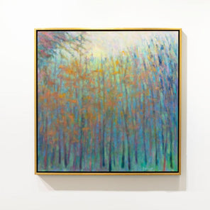 A colorful abstracted landscape painting framed in a gold frame hangs on a white wall. 