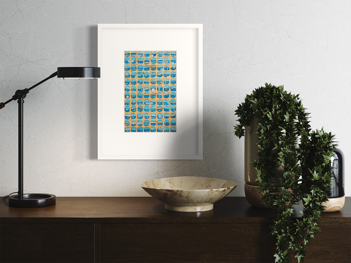 An orange, blue and light blue abstract print in a white frame with a mat hangs on a white wall above a dark wood surface with a black desk lamp, a beige bowl and two vases covered with greenery.