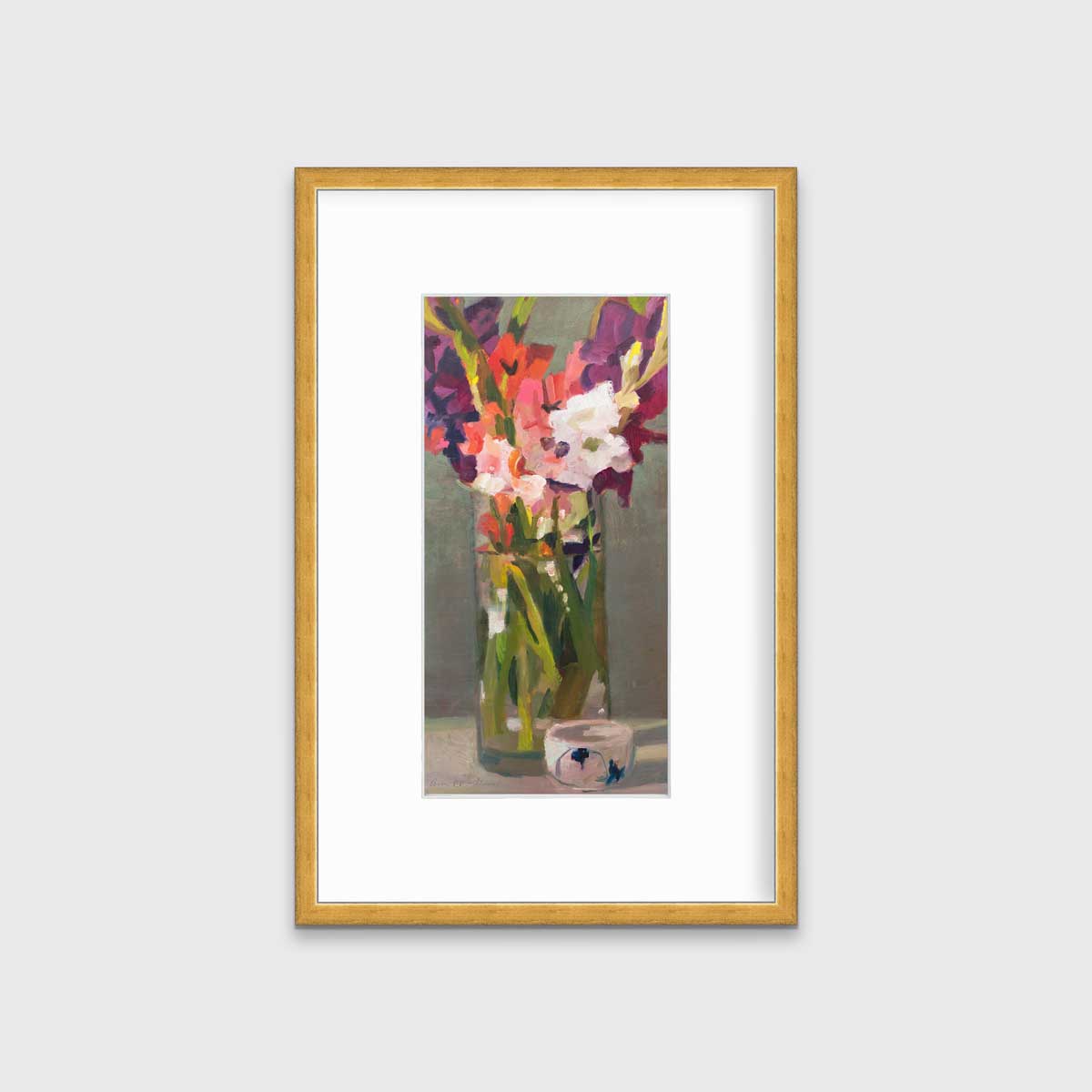A purple, pink and green abstract floral print in a gold frame with a mat hangs on a white wall.