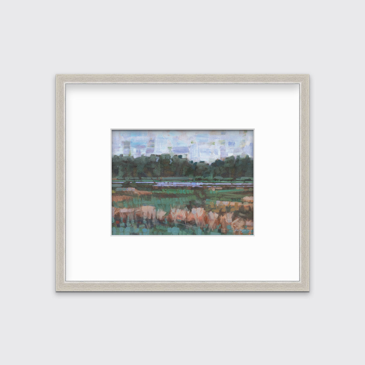 A green, orange and blue abstract landscape print in a silver frame with a mat hangs on a white wall.