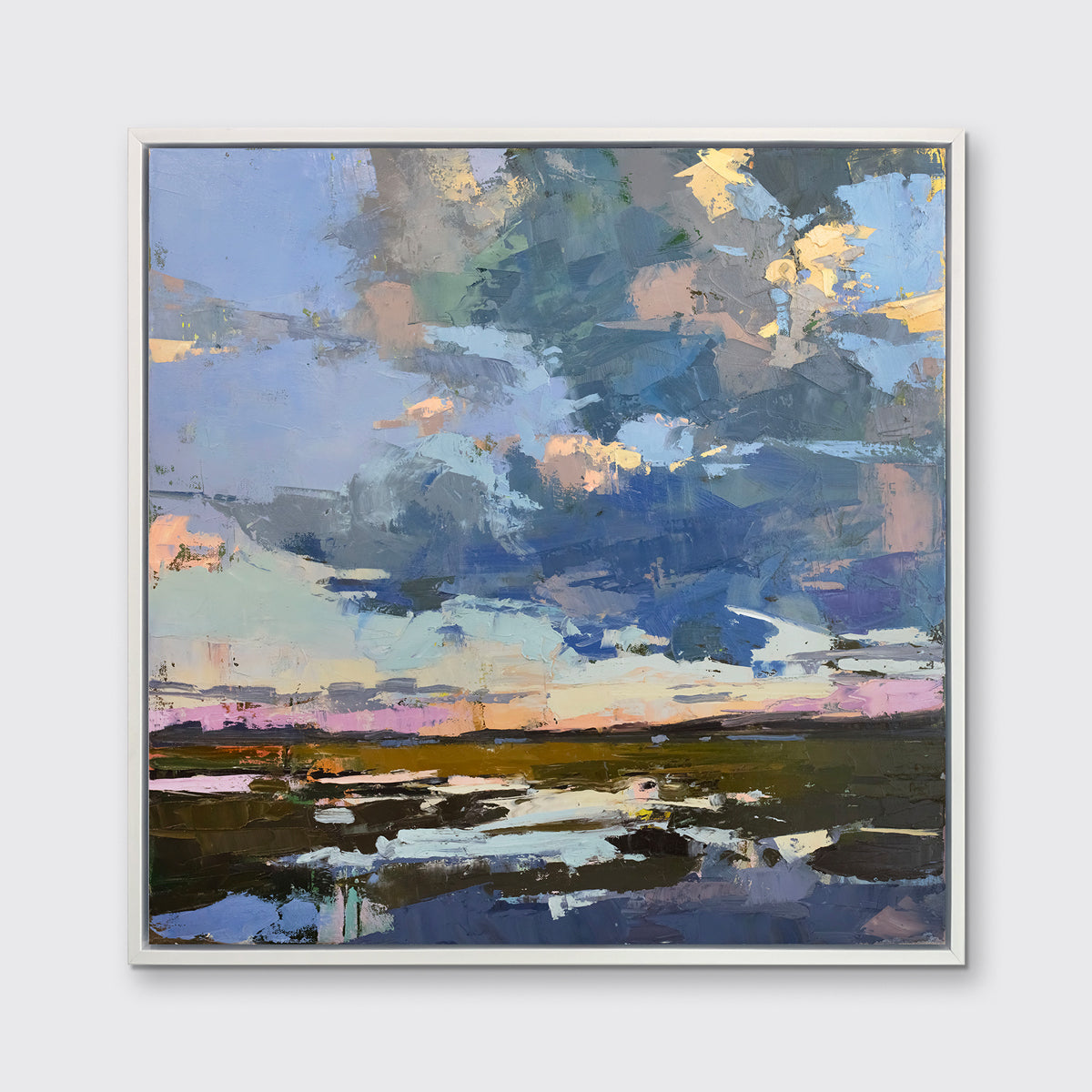 A blue coastal landscape art print framed in a white frame hangs on a white wall.