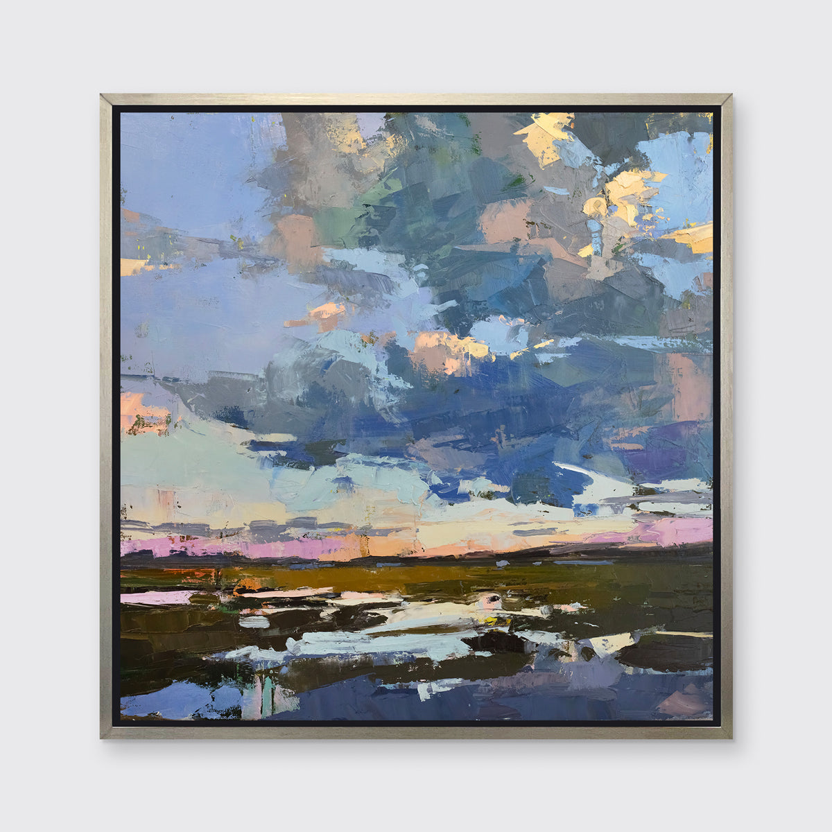 A blue coastal landscape art print framed in a silver frame hangs on a white wall. 
