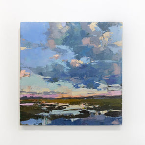 A blue abstract landscape painting hangs on a white wall. 