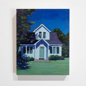 A landscape painting of a white house, lit by moonlight with a dark sky and a large tree to the left side by Carol Young hangs on a white wall.