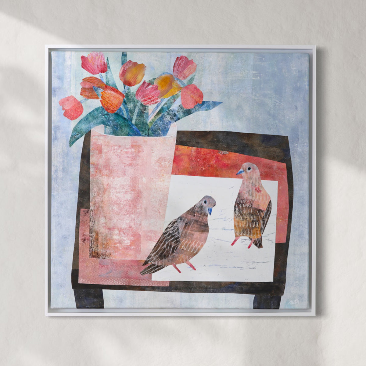 A framed collage featuring two birds and a bouquet of tulips, displayed on a textured light gray wall with soft shadows.