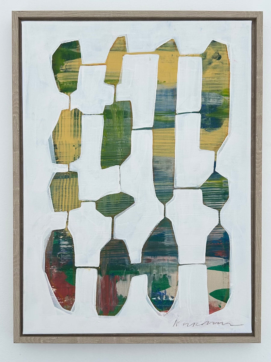 A framed abstract painting featuring geometric shapes in various colors displayed on a wall.